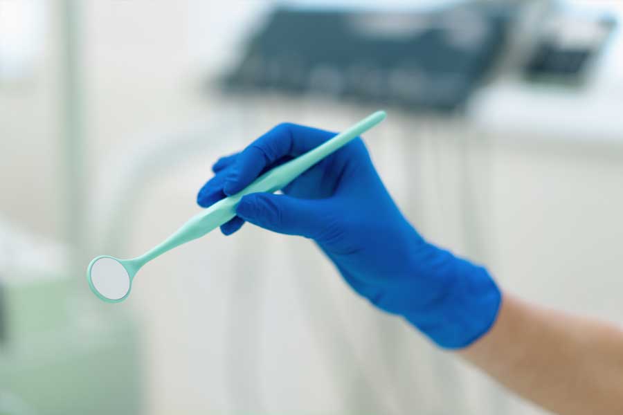 Dental professional holding a mirror during oral surgery exam or dental consultation.