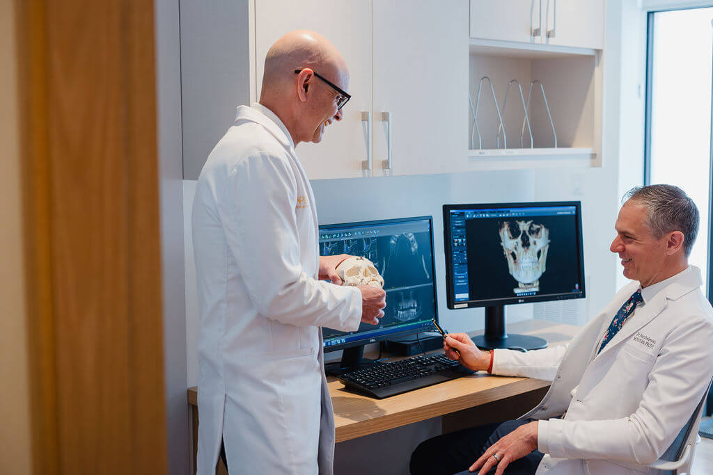 Apex Surgical oral surgeons reviewing 3D dental scans and skull model for treatment planning.