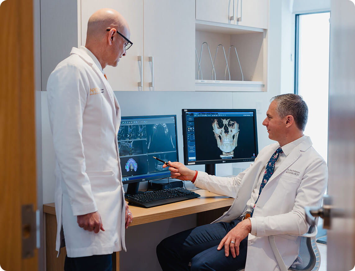Apex Surgical oral surgeons reviewing 3D dental imaging for oral and maxillofacial treatment planning.